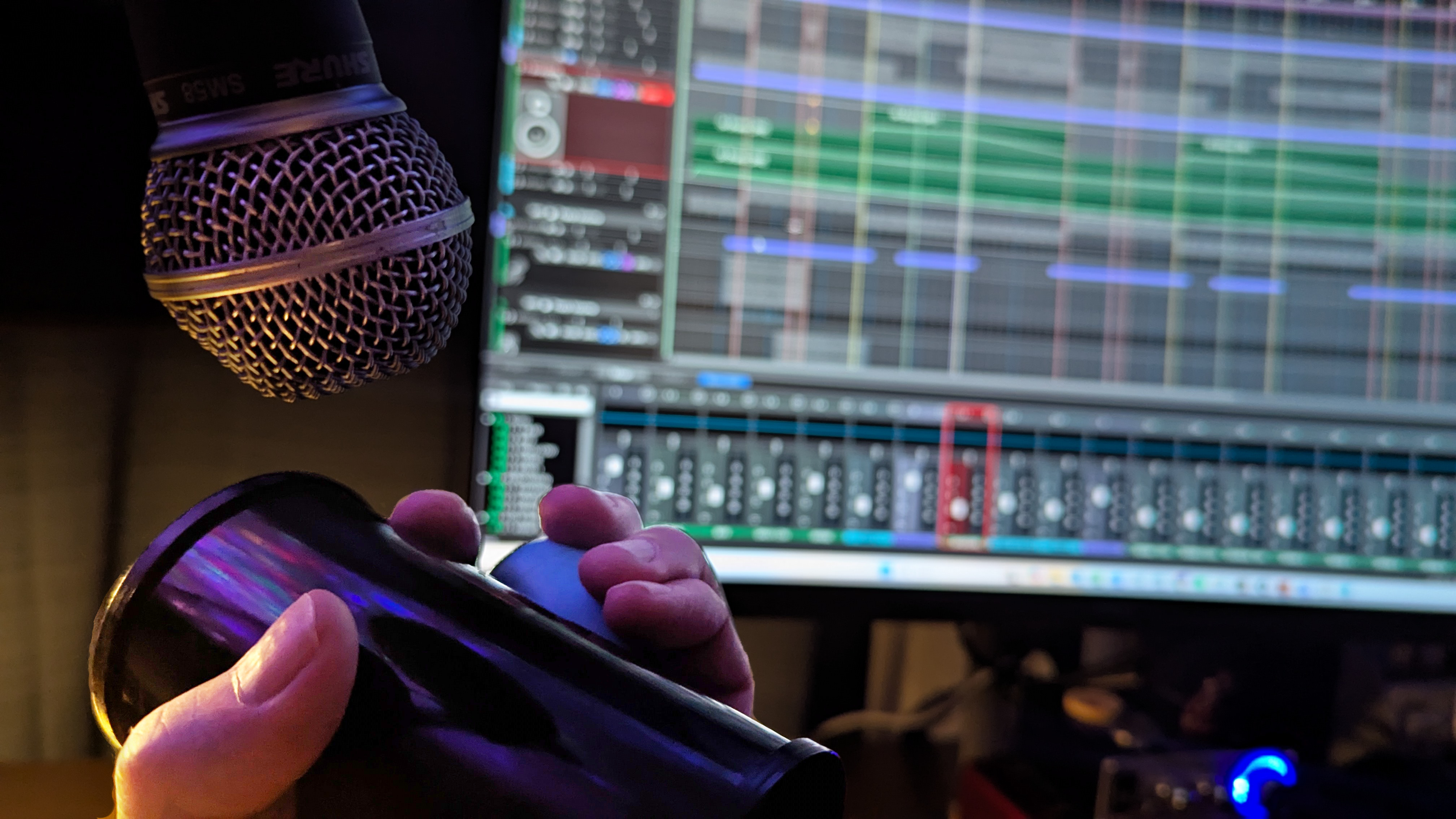 Two shakers held beneath an inverted microphone with the recording session blurred behind
